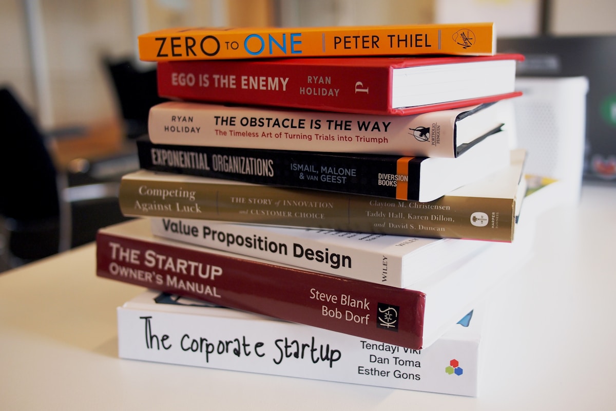 A stack of personal-development books on a light desk